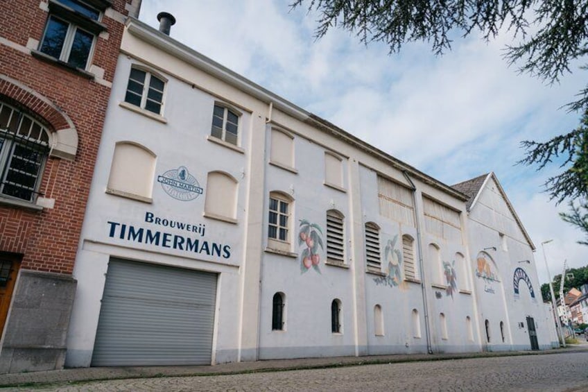 A building with 'Brouwerij TIMMERMANS' signage, featuring a white facade with murals and a large garage door. 5