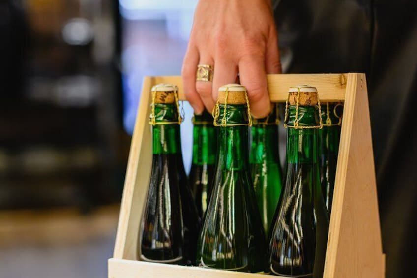 A wooden crate holding several green bottles with corks. 2