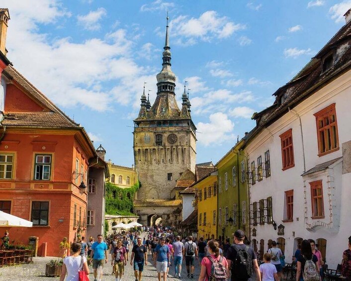 A crowded street with historic buildings and a prominent tower. 5