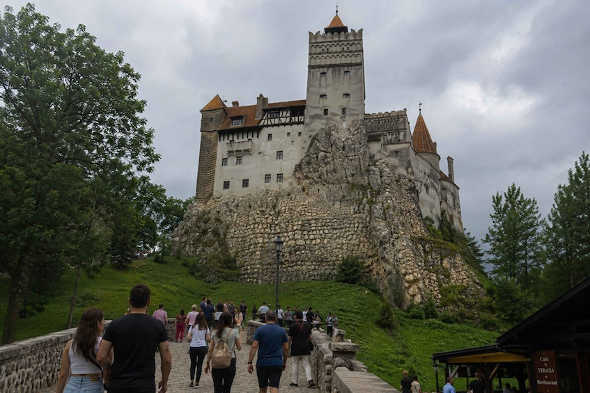 A castle on a hill with tourists walking towards it. 1