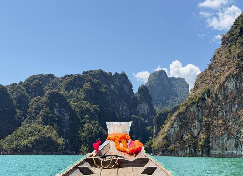 A boat with a wooden structure and orange decorations on the bow, surrounded by turquoise water and limestone cliffs. 4