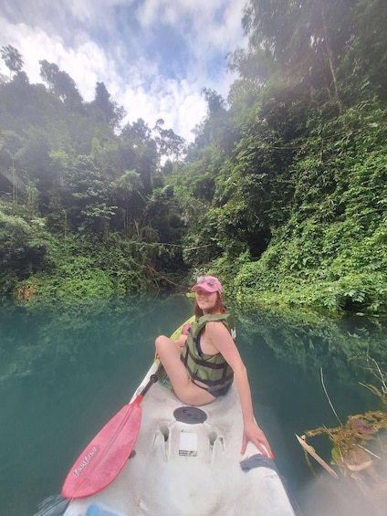 A person kayaking on a river surrounded by dense greenery. 3
