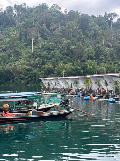 A calm lake with boats, a dock, and a forested hillside in the background. 5