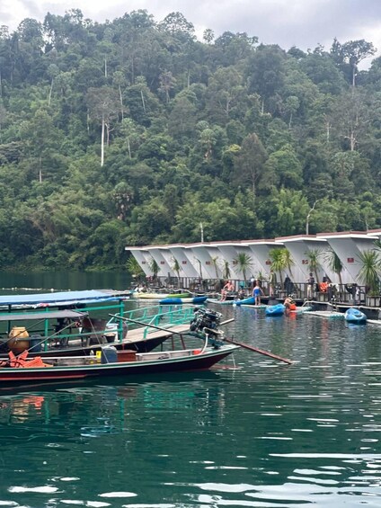 A calm lake with boats docked near a building surrounded by lush greenery. 5