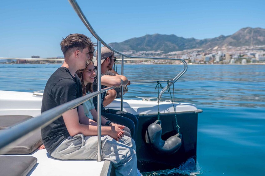Two people on a boat with a city and mountains in the background. 5