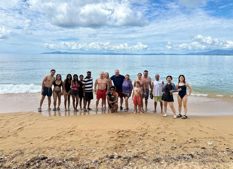 A group of people on a sandy beach with a calm sea and distant mountains. 4