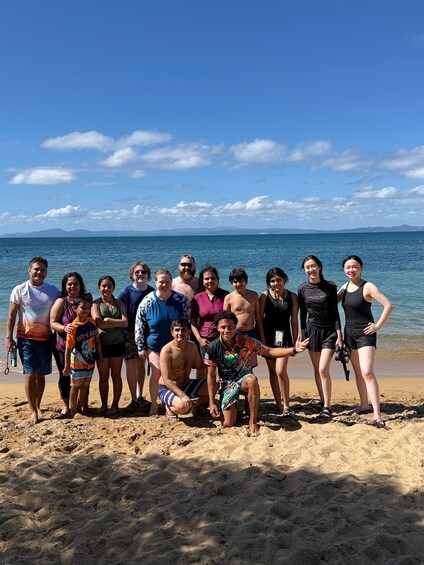 A group of people on a sandy beach with a clear blue sky and calm sea in the background. 5