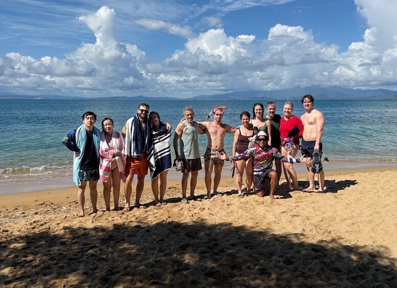 A group of people on a beach with the ocean and mountains in the background. 2