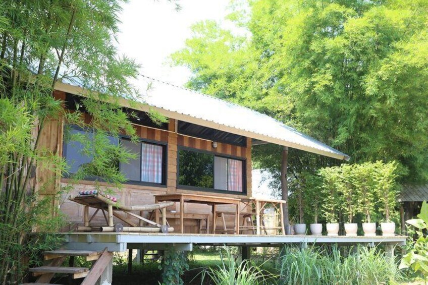 A wooden house with a balcony, surrounded by bamboo and trees. 4