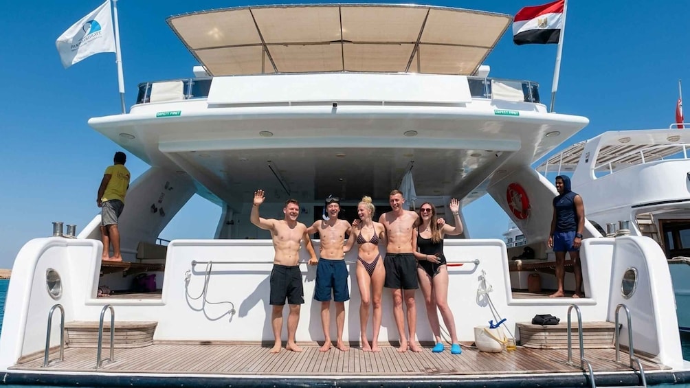 A group of people on a boat deck with safety signs and flags. 1