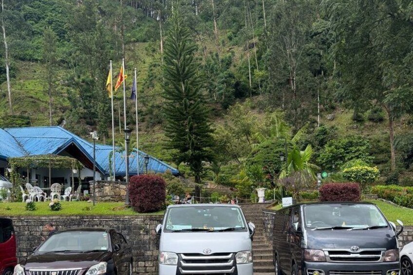 A parking area with cars, a building with a blue roof, and flags. 2