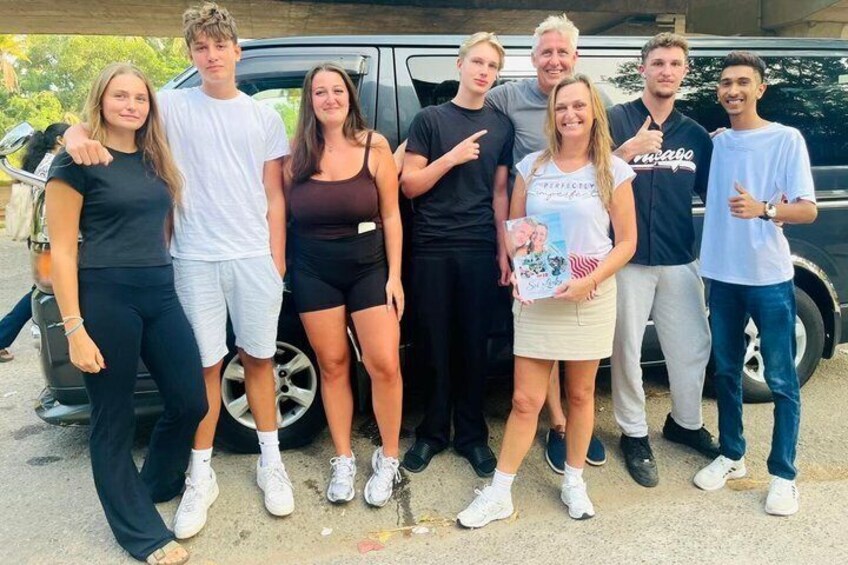 A group of people standing in front of a vehicle. 1