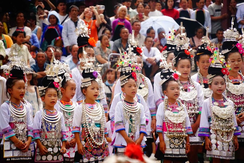 A group of people in traditional attire with elaborate headdresses and jewelry, participating in a cultural event. 1