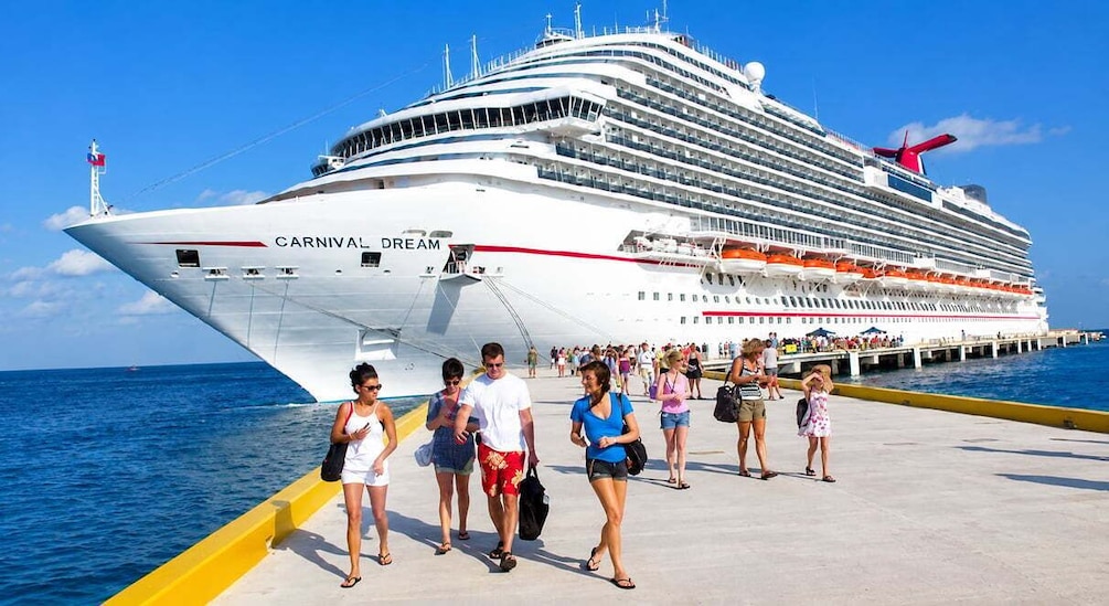 A large cruise ship named 'Carnival Dream' docked at a pier with people walking along the pier. 1