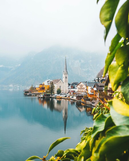 A serene lakeside town with a prominent church, colorful buildings, and a calm water body reflecting the architecture. 3