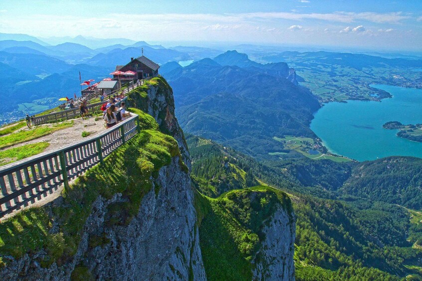 A mountain overlook with a wooden viewing platform, a lake, and distant mountains. 1