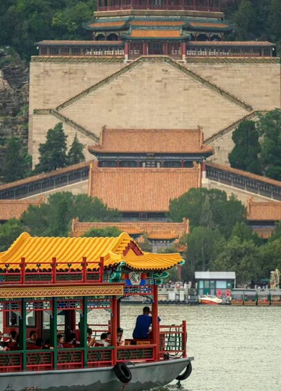A traditional Chinese pavilion with a yellow roof, a boat with passengers, and a large historical building in the background. 1