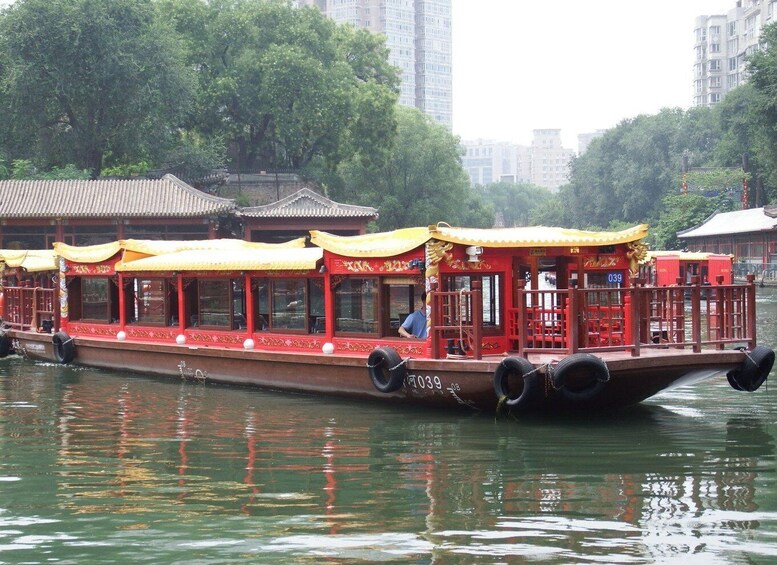 A traditional red boat with yellow canopies, number 039, on a river with buildings in the background. 2