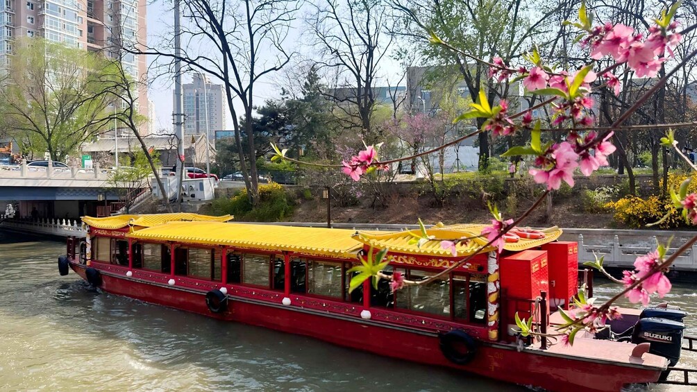 A red boat with yellow canopies on a river, surrounded by trees and buildings. 3