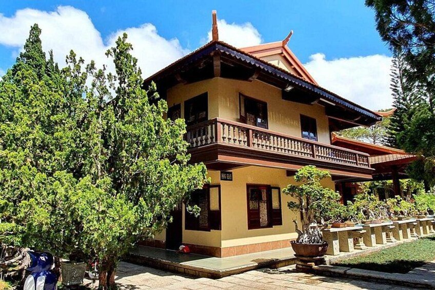 A two-story building with a balcony, surrounded by trees and a well-maintained garden. 3