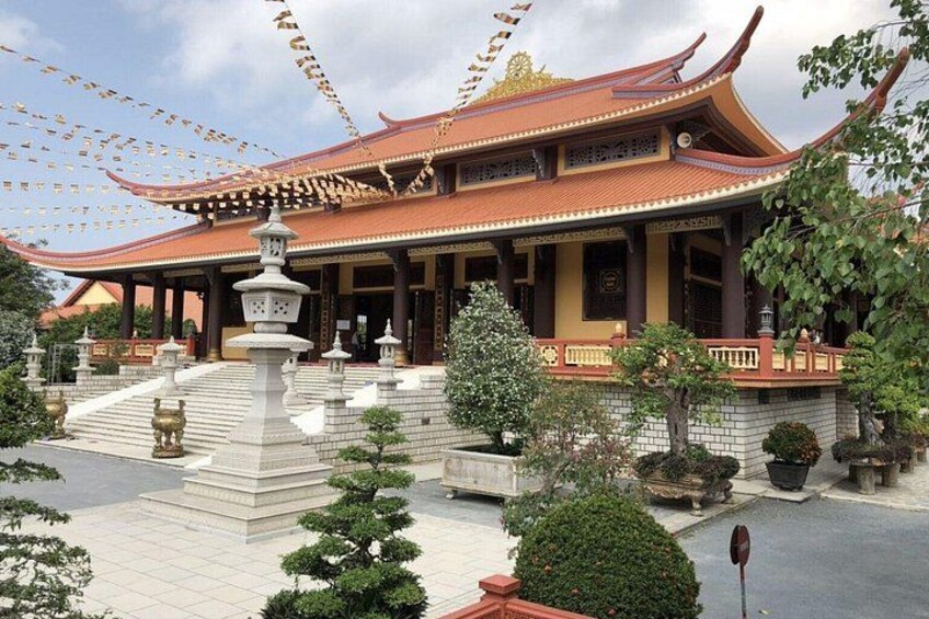 A traditional temple with a curved roof, a central pavilion, and a well-maintained garden with trees and a stone lantern. 4