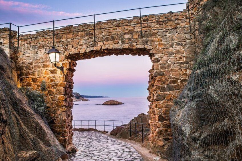 A stone bridge with a lantern, leading to a coastal view. 3