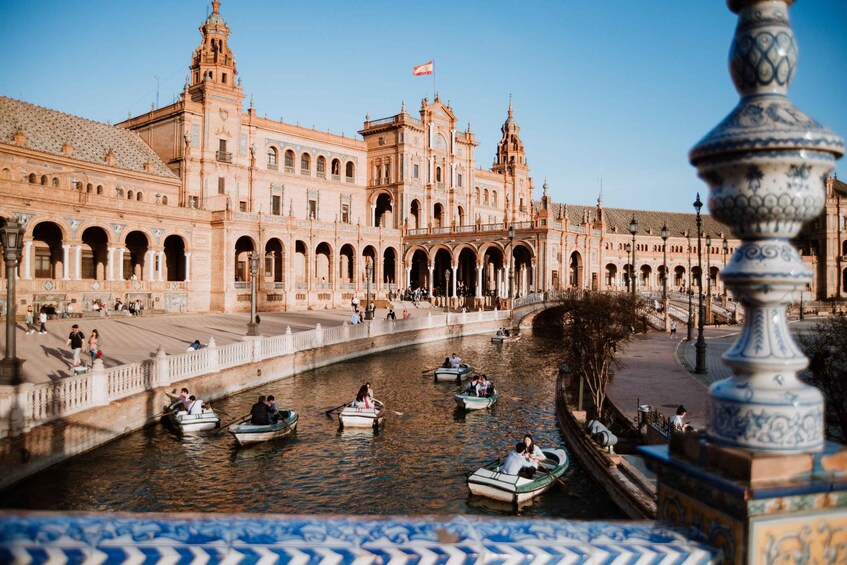 A historic building with arches and a river with boats. 4