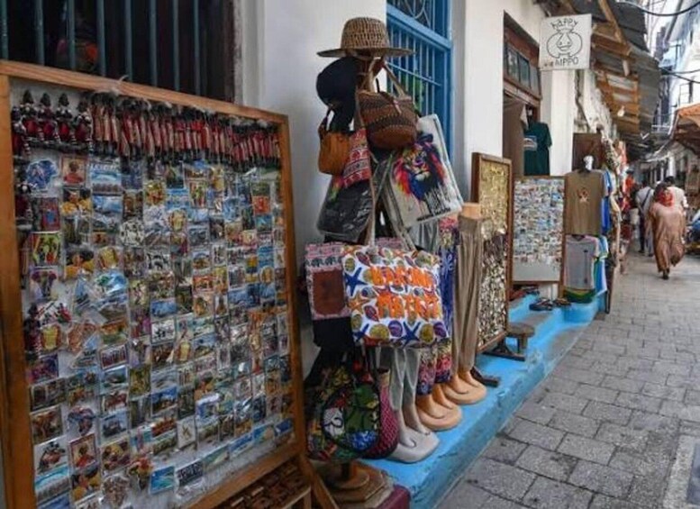 A street market with various stalls selling souvenirs, postcards, and colorful bags. 5