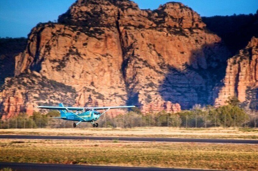 A small blue aircraft on a runway with a mountainous landscape in the background. 4