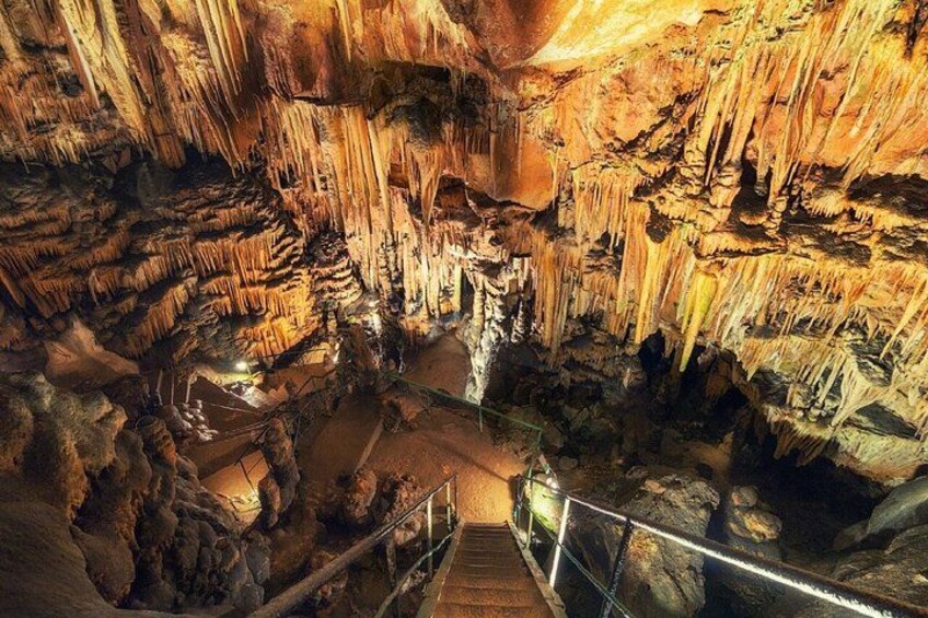 A cave with stalactites and stalagmites, a staircase, and a light source. 2