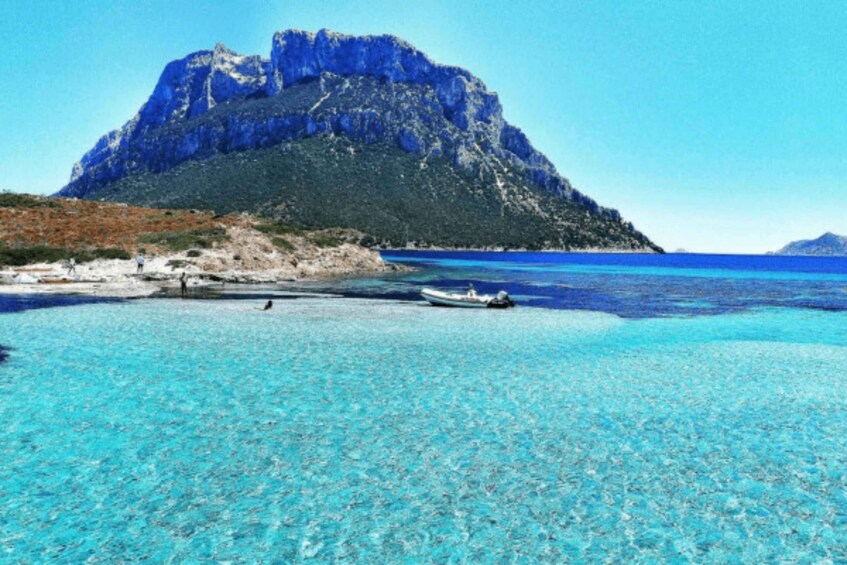 A clear turquoise sea, a rocky cliff, and a small boat. 2