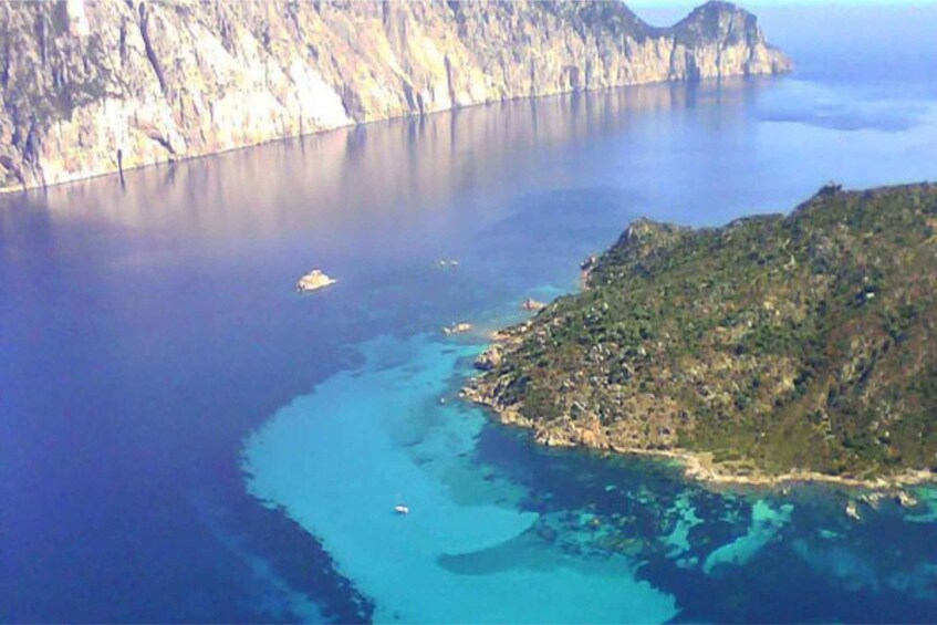 A coastal landscape with a clear blue sea, a small island, and a steep cliff. 4