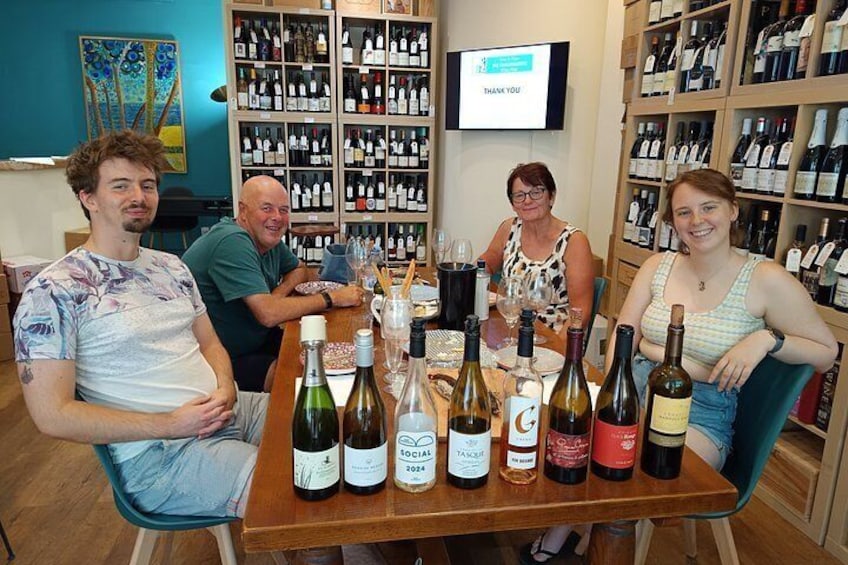A group of people seated at a table with wine bottles and glasses. 5
