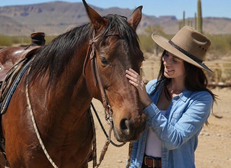 A person in a denim shirt and hat interacting with a horse in a desert landscape. 3
