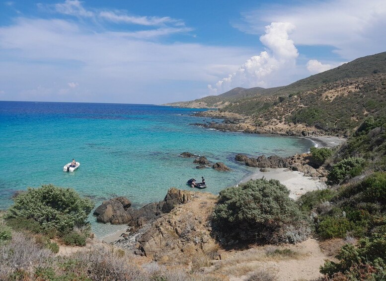 A coastal landscape with clear turquoise waters, rocky shores, and sparse vegetation. 4