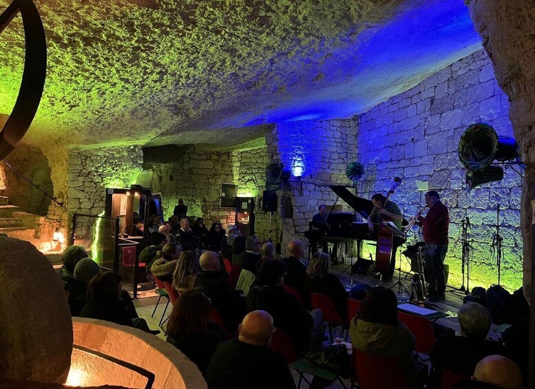 A band performing in a stone-walled venue with a seated audience. 3
