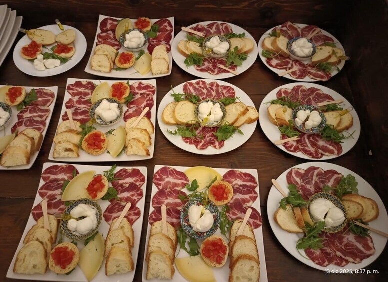 Multiple plates of charcuterie with bread, cheese, and arugula. 5