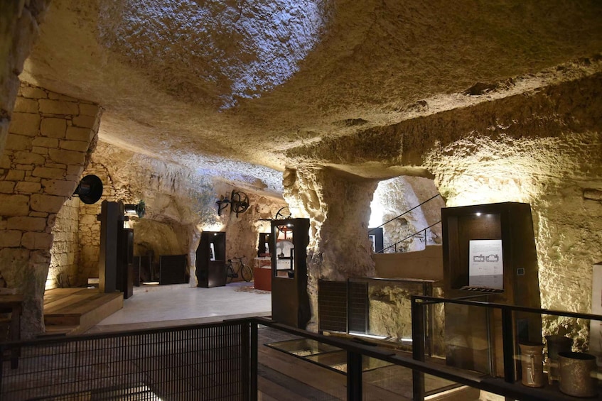 An underground passage with stone walls, a wooden floor, and a glass railing. 1