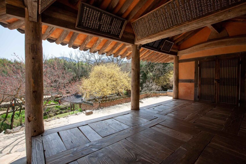 A traditional wooden structure with a tiled roof, surrounded by a garden with a stone pathway and a tree. 4