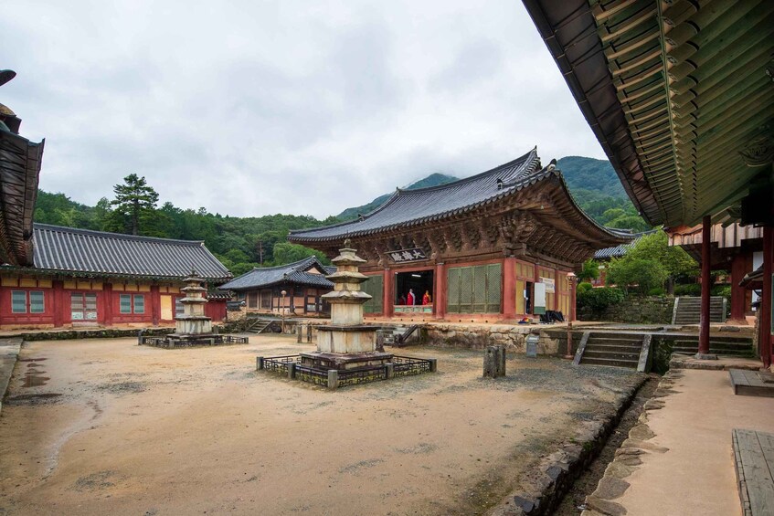 A traditional Korean temple complex with a stone pagoda, wooden buildings, and a mountainous backdrop. 3