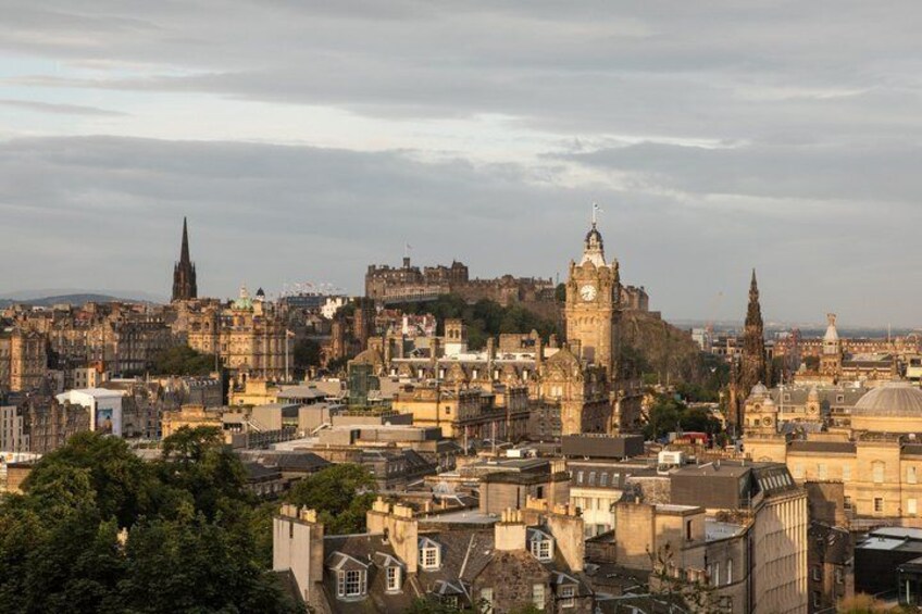 A cityscape with historic buildings, a prominent clock tower, and a castle on a hill. 1