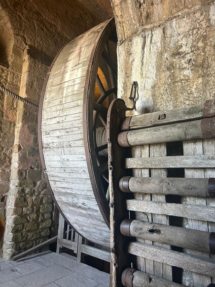 A large wooden wheel attached to a stone wall. 4