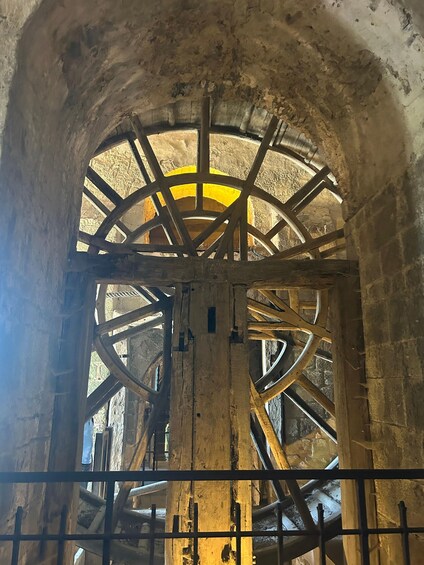 An ancient stone structure with a large, circular, metal-framed wheel. 2