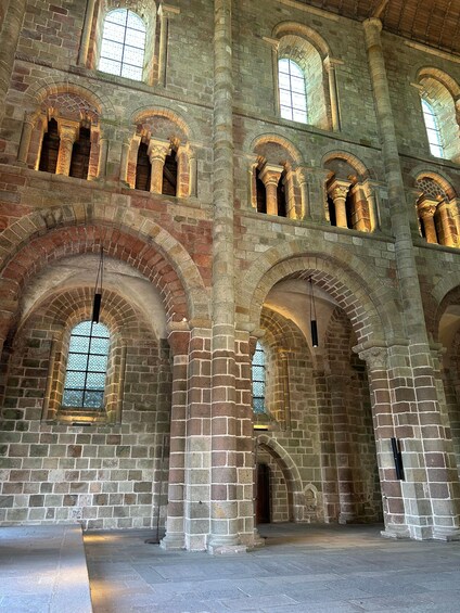 An interior with stone arches, columns, and arched windows. 3