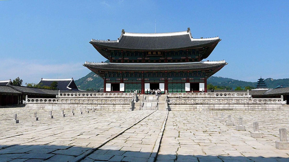 A traditional Korean building with a multi-tiered roof and stone steps leading up to it. 5