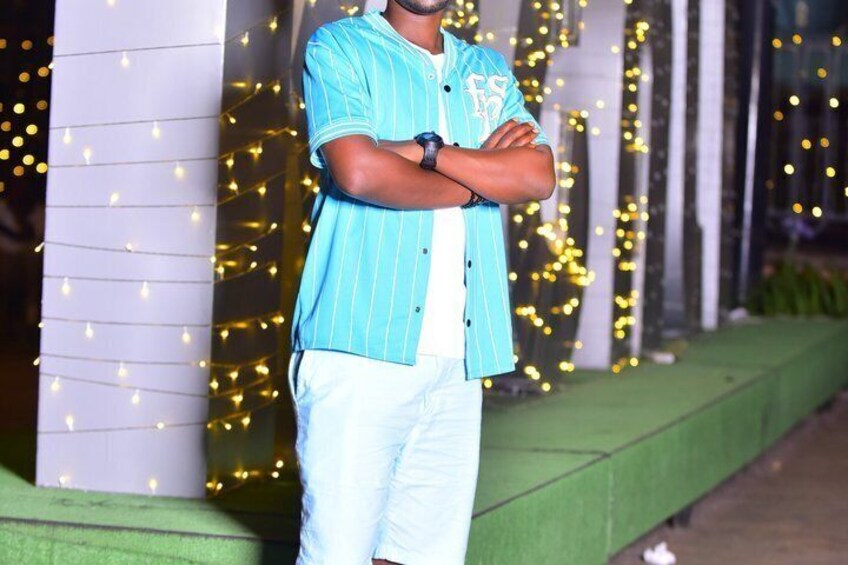 A person standing with arms crossed in front of a building with string lights. 5