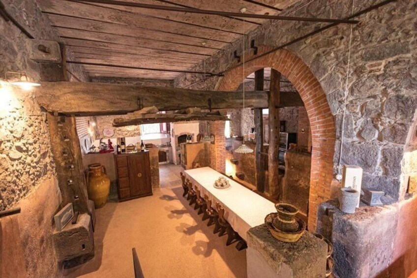 A rustic kitchen with stone walls, wooden beams, and a long counter. 3
