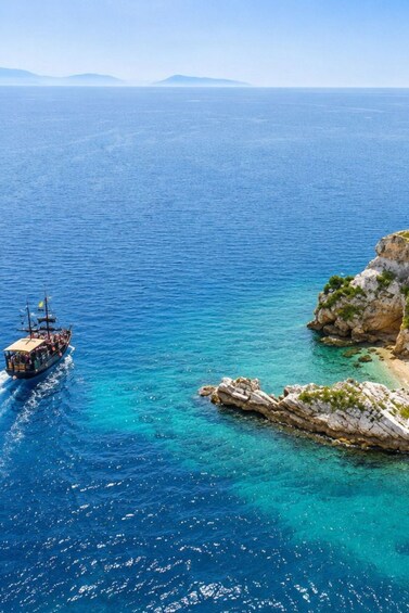 A boat sailing near rocky coastlines with clear blue waters. 5