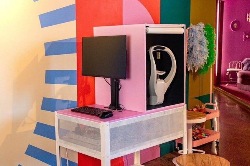 A pink and white computer setup on a white table with a black monitor, keyboard, and white speaker. 2