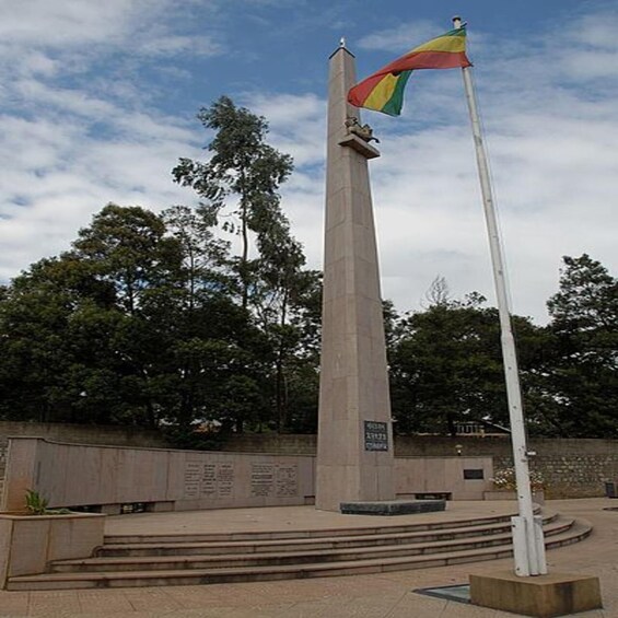 A tall monument with a flagpole, surrounded by steps and a plaque. 5